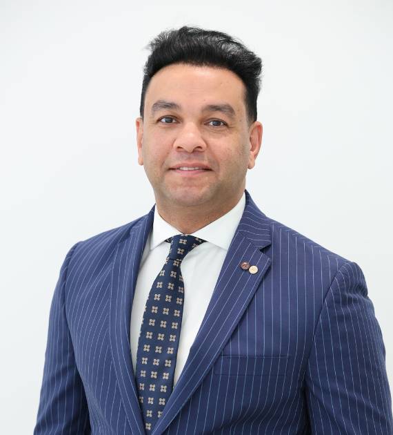 E hab Shahein, Procurement Manager, Trojan Property Investment (TPI) - Smiling man in a blue pinstripe suit and patterned tie against a white background, conveying professionalism and confidence in a formal business setting.
