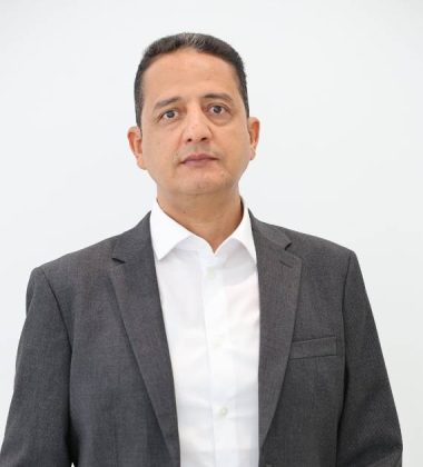 Ababakr Mansour, Senior Project Manager, Trojan Property Investment (TPI) - Business professional wearing a grey suit and white shirt standing against a white background looking directly at the camera with a neutral expression.